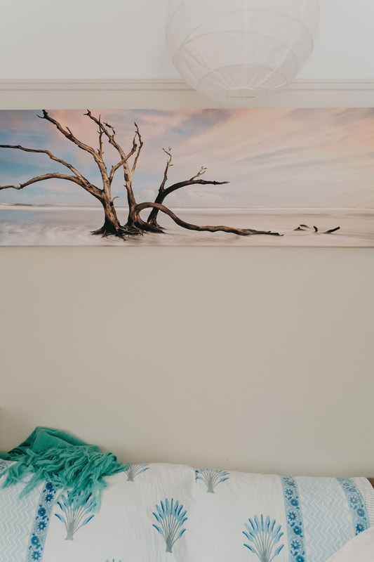 Comfortable couch with a painting on the wall above showing a beach scene